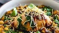Samosa Chaat · Vegetable samosas topped with chickpeas, onions, tamarind and mint sauces with spiced yoghurt.