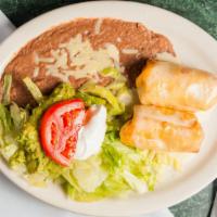 Chimichagas · Two beef tips or chicken fried chimichangas, topped with cheese dip. Served with beans, guac...