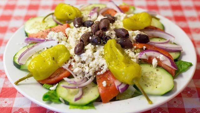 Greek Salad · Romaine lettuce, tomatoes, cucumbers, onions, black and kalamata olives, and pepperonccini peppers and covered by mounds of feta cheese.