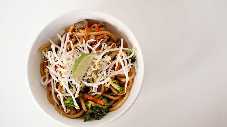 Spicy Japanese Noodles (Cannot Be Made Gluten Free) · Thick udon noodles spiked with sugar-lime soy sauce and loaded with fresh broccoli, carrots, and mushrooms. Topped with bean sprouts and a lime wedge.