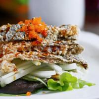 Salmon Skin Salad · Crispy salmon skin beds on sliced cucumber, topped with Caviar, scallion, sesame seeds and e...