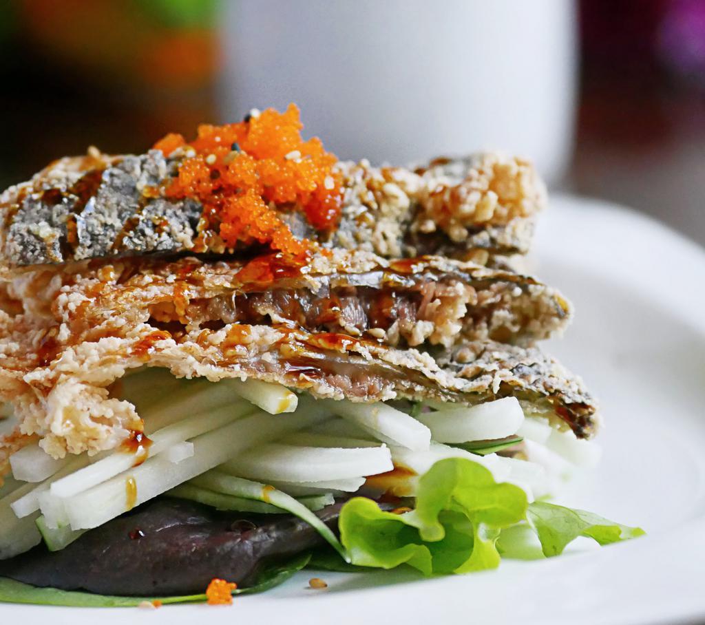 Salmon Skin Salad · Crispy salmon skin beds on sliced cucumber, topped with Caviar, scallion, sesame seeds and eel sauce.