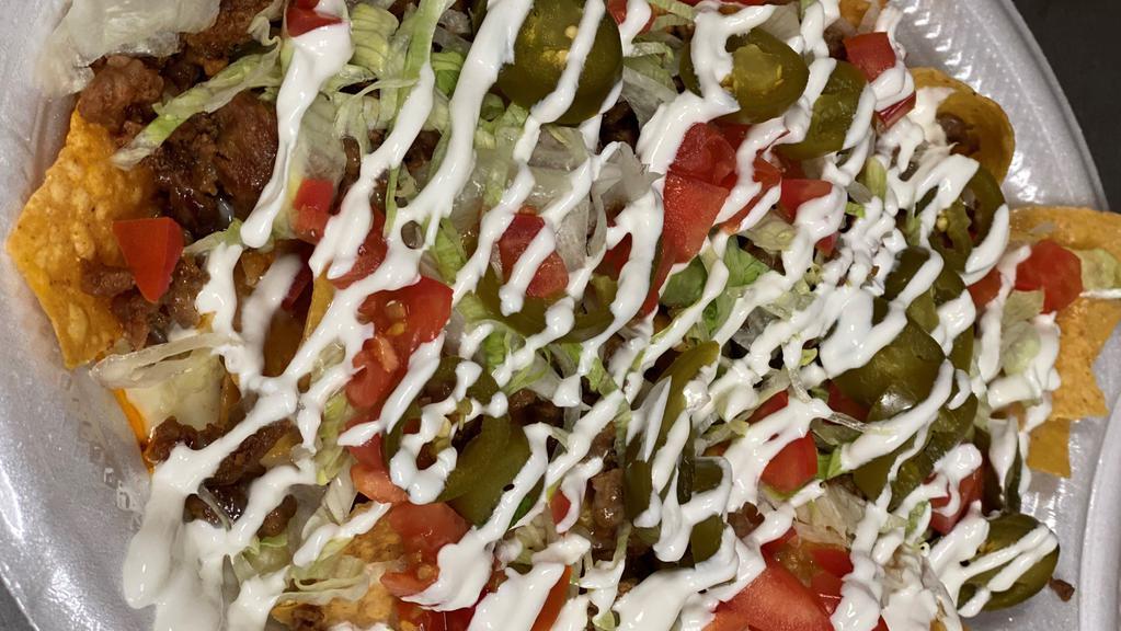 Nachos: Carne Asada///Steak · in-House fried tortilla chips with steak, chopped tomatoes, shredded lettuce, jalapenos, sour cream and melted queso dip