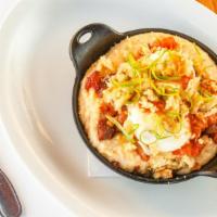 Breakfast Crumble · Crumbled buttermilk biscuit, grits, tomato gravy, crumbled bacon, two eggs, and green onions.