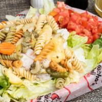 Turkey, Pasta & Green Salad · A large plate of green salad topped with fresh turkey breast and vegetable pasta.