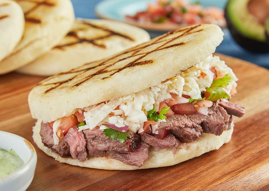 Arepa Carne Asada · Arepa Grilled steak, green cabbage, paisa cheese, pico de gallo with our home made garlic sauce.