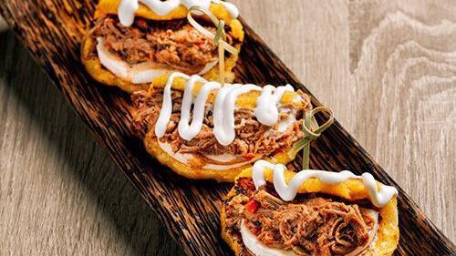 Las Cachapas Con Mechada · Trio of Venezuelan style sweet corn pancakes filled with queso e' mano, shredded beef and topped with nata.