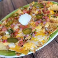 Macho Nachos · Crispy corn tortilla chips piled high with refried beans, jalapenos, queso, melted jack and ...