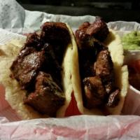 Tacos Al Carbon · Two handmade corn tortillas filled with slices of sirloin steak or chicken. Served with chee...