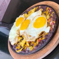 Huevos Rancheros · 3 eggs in a bed of black beans, pico de gallo and nachos with cheddar cheese on top