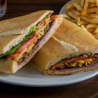 Pan Con Bistec · Palomilla steak cooked with onions, ham, potato sticks, lettuce, and tomatoes.