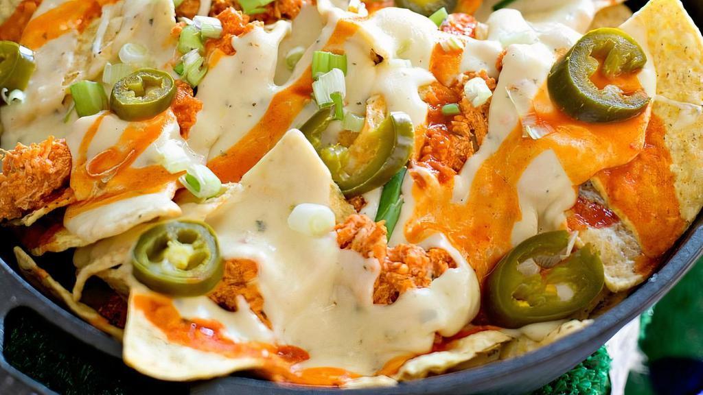 Loaded Buffalo Chicken Nachos · Fried tortilla chips topped with buffalo chicken, bleu cheese crumbles, buffalo sauce, scallions, jalapenos and drizzled in ranch dressing