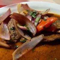 *Bistec Encebollado · Flank steak with onions, cilantro, and tomatoes served with rice.