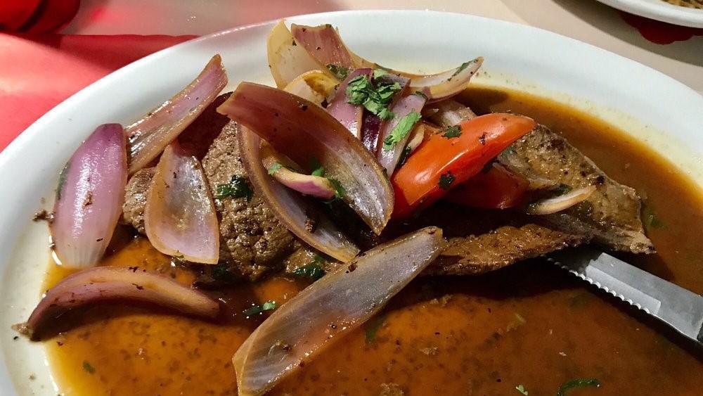 *Bistec Encebollado · Flank steak with onions, cilantro, and tomatoes served with rice.