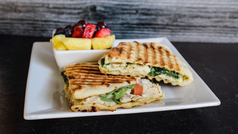 Chicken Basil Pesto Panini · All-white meat chicken, basil pesto, havarti cheese, spinach, tomato, pressed on naan bread. With a side of chips or fruit.