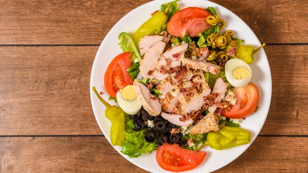 Cobb Salad · Tomatoes, red onions, green peppers, cucumbers, blue cheese, crumbles, bacon, grilled chicken, hard-boiled egg, pepperoncinis, green, and black olives.