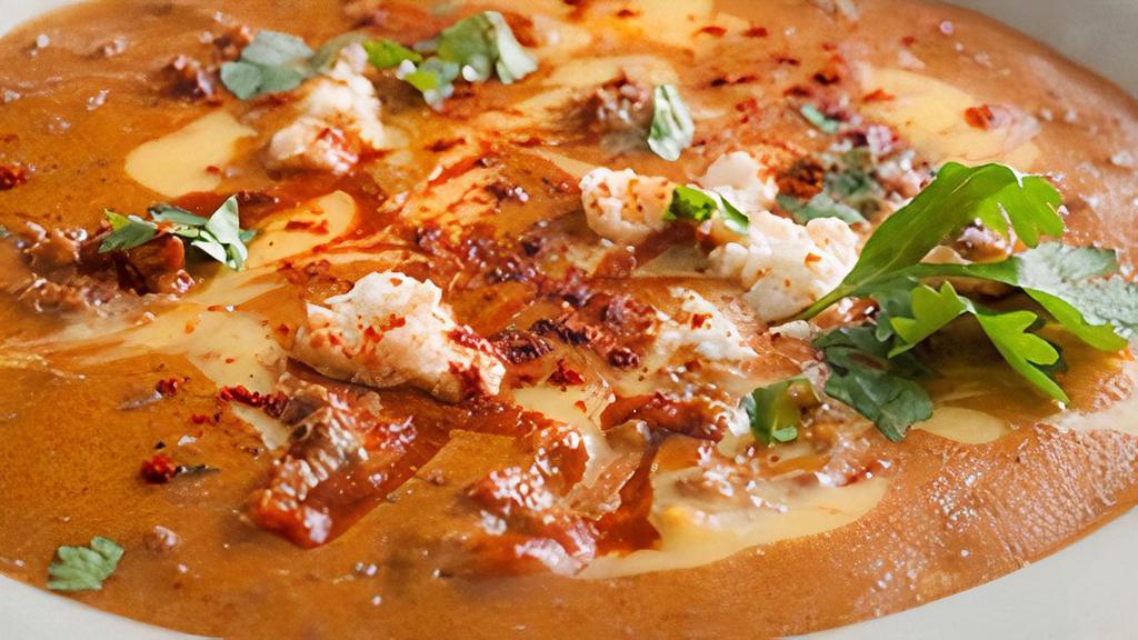 Queso Diablo · A flavorful cheese dip made with seasoned ground beef, slow-roasted peppers and chiles, topped with queso fresco, Cholula salsa and cilantro.