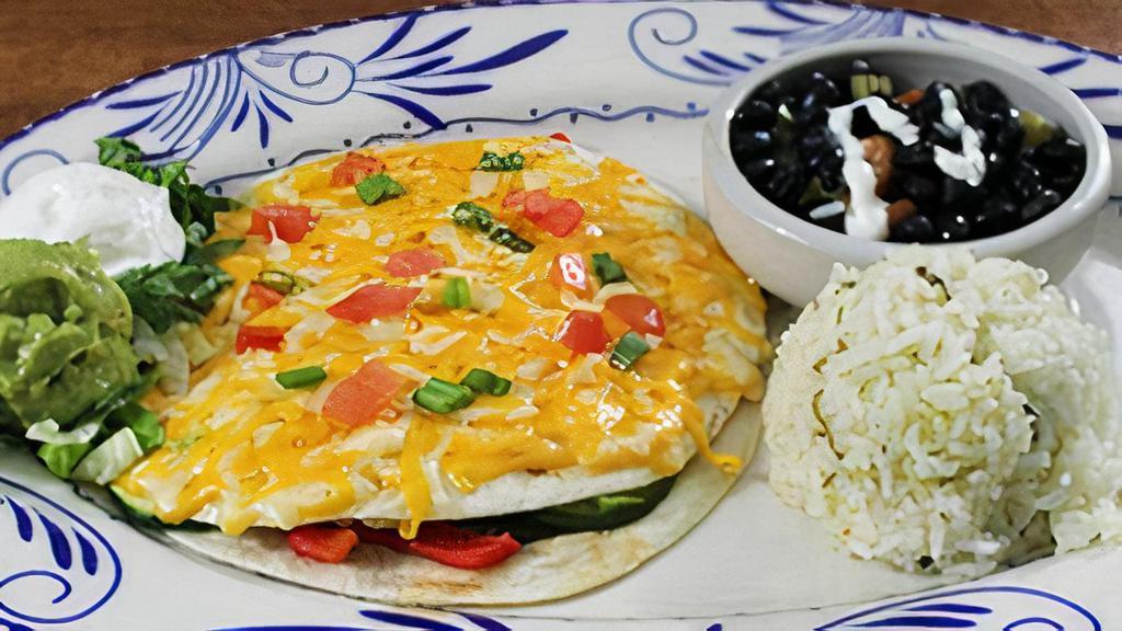 Vegetarian Quesadilla Al Horno · Oven baked quesadilla filled with vegetables and topped with blended cheeses. Served with cilantro lime rice and black beans.