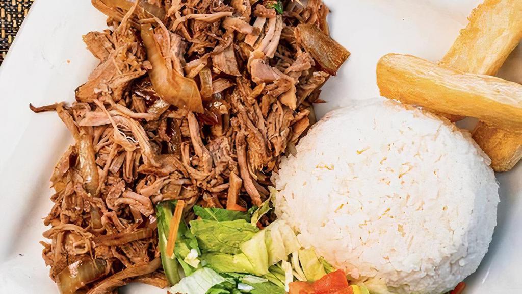 Lechon Asado · Slow roasted pork marinated in a traditional sour orange mojo. Served with white rice, yuca fries, garlic mojo, and salad.