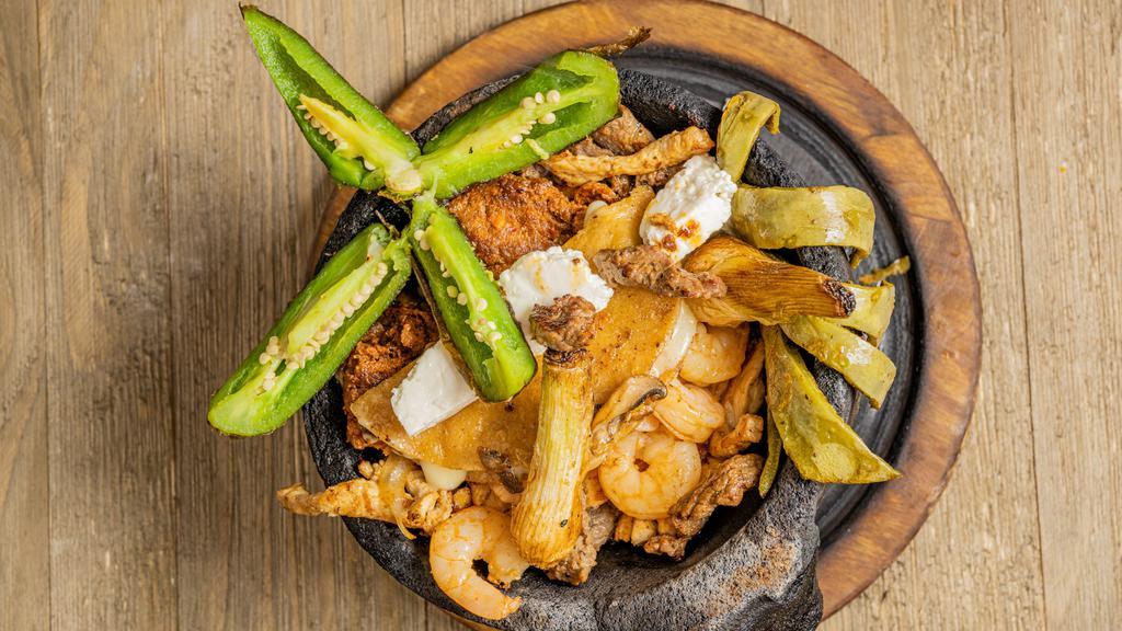 Adan Molcajete · Grilled steak, shrimp, chicken, sausage, cheese quesadilla, queso fresco, Mexican cactus, chile toreado and onions. All on a bed of grilled onions and bell peppers.