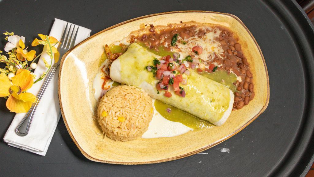 Burrito Al Pastor · A flour tortilla stuffed with pork grilled onions and pineapple covered with cheese sauce, green sauce, and garnished with pico de allo. Served with rice and charros beans.