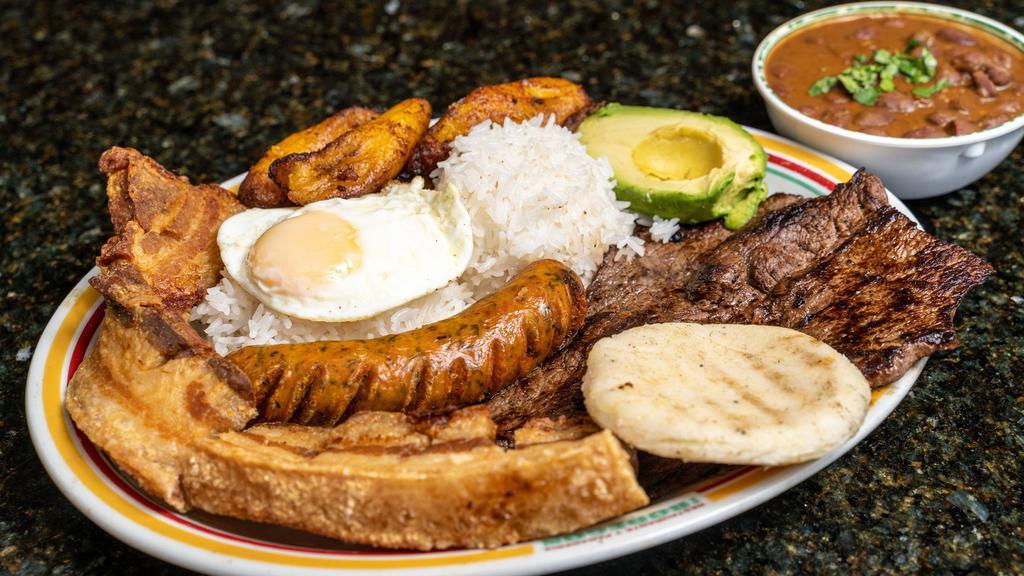 Bandeja Paisa / Paisa Platter · Un plato completo de carne, chorizo, chicharrón, arroz, frijoles, maduros y un huevo. / A full platter of beef, chorizo, pork rinds, rice, beans, fried sweet plantains, and an egg.