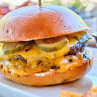 *The Tavern Burger · Two burger patties are layered with American cheese, house-made pickles, and garlic aioli.
