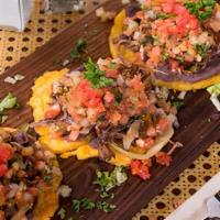 Tostones Rellenos · 3 tostones served with a choice of chicken, pork, beef or shrimp topped with black bean pure...