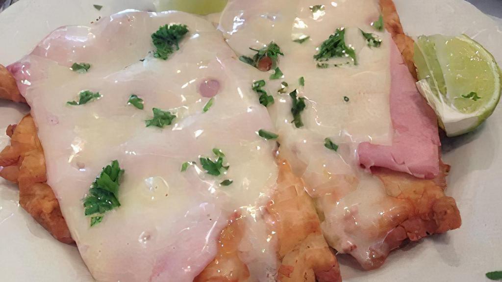 Milanesa De Pollo · Breaded boneless chicken breast topped with marinara sauce, ham and melted mozzarella cheese.