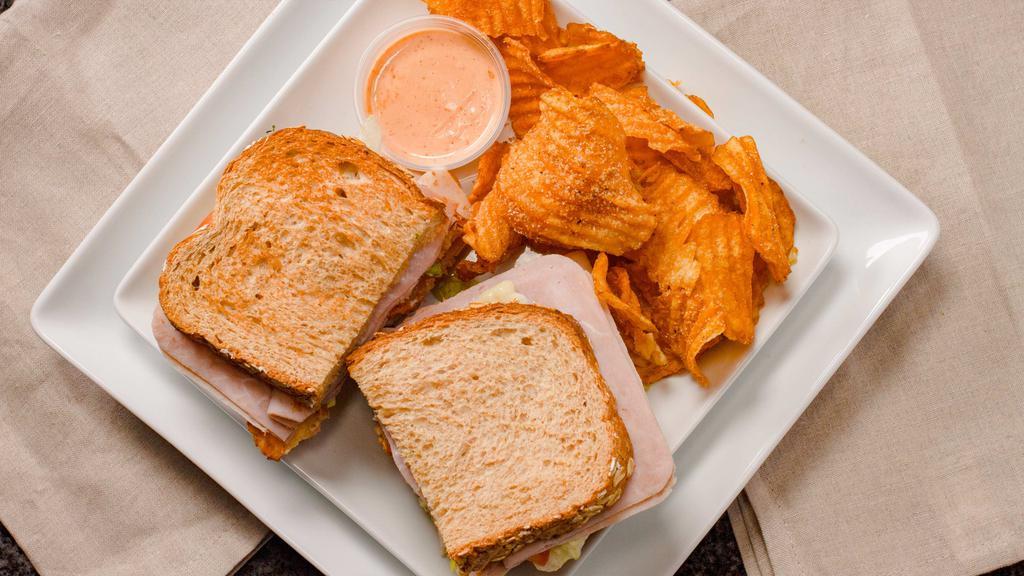 The King Of Clubs Sandwich · Triple decker sandwich on toasted wheat with sliced ham, sliced turkey, and strips of bacon. Topped with lettuce, tomato, and mayonnaise. Served with choice of our homemade chips, French fries, or baked potato salad.