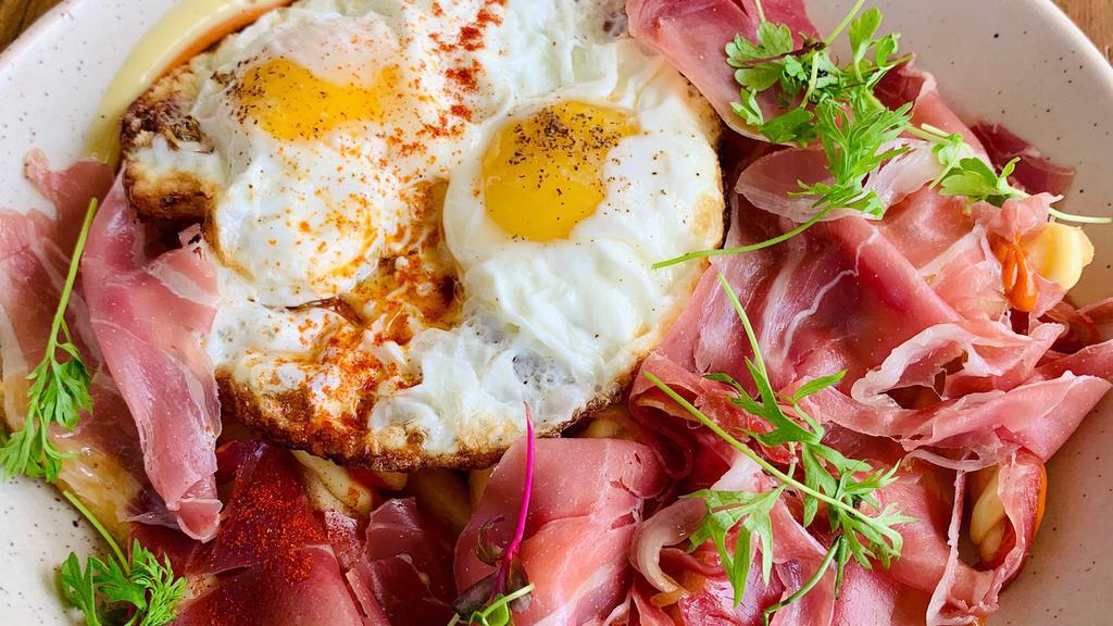 Broken Eggs · Kow version of the Spanish classic huevos rotos. Serrano ham and Italian parsley on a bed of fried potatoes topped with two sunny side up eggs.