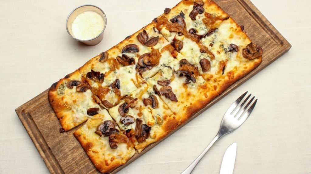 Mushroom Flatbread · Baked ricotta, mozzarella, parmesan, and blue cheese, mushrooms, and caramelized onions. Finished with truffle oil.