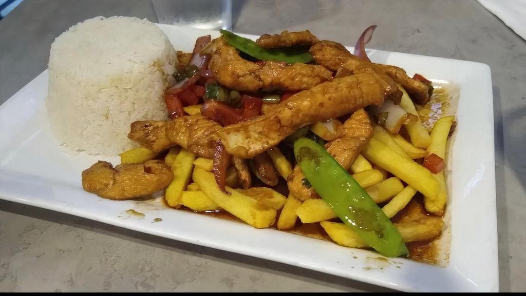 Pollo Saltado · Sautéed chicken with onions, tomatoes, red peppers, and green onions. Served with white rice and fries. Pictured with fried rice.