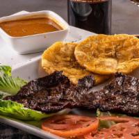 Carne A La Parrilla · Grilled steak with rice, beans, and fried green plantain.