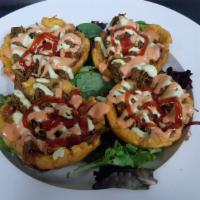 Beef Tostones · Green plantain basket with beef, cheese, pink sauce, green sauce (garlic) and ketchup.