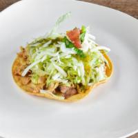 Tostada · Fresh crispy open face corn taco shell served with beans, meat and topped with lettuce, chee...