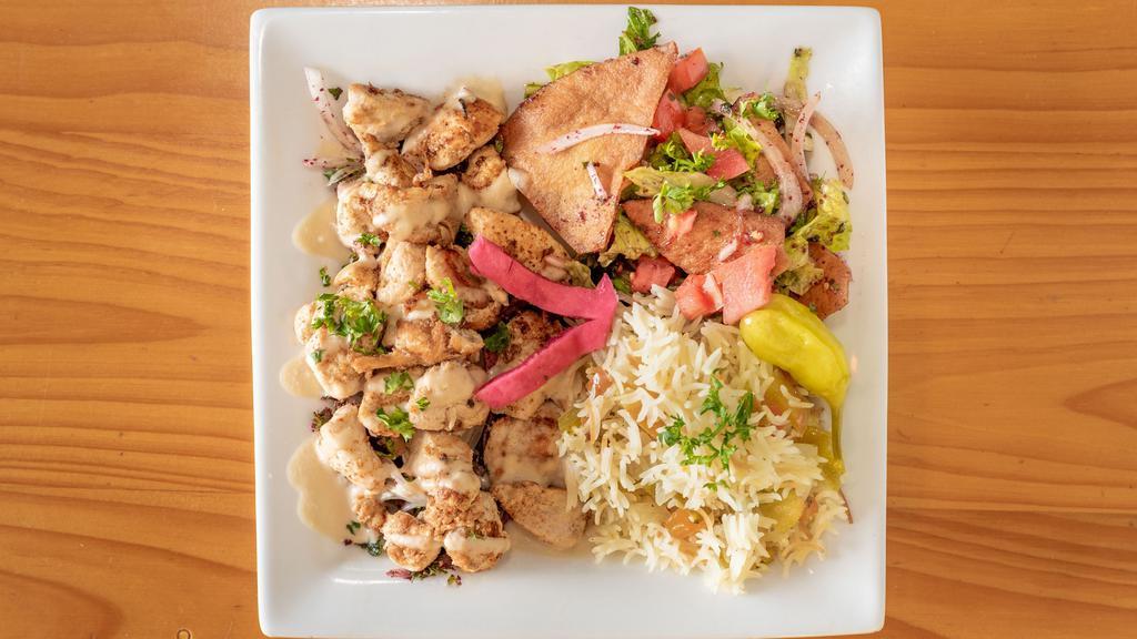 Chicken Shawarma Plate · sliced marinated chicken breast on top of parsley and onions topped with our homemade tahini sauce with a side of garlic sauce