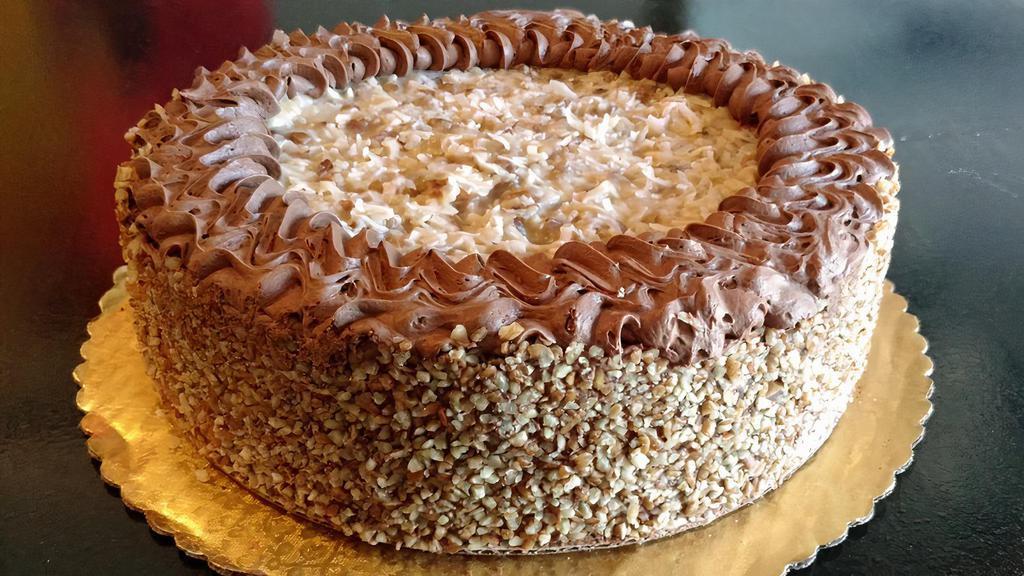 German Chocolate Cake · Dark chocolate layers baked with chocolate chunks, filled with our own German chocolate custard and frosted with our rich chocolate butter cream frosting. Toasted pecans are added to the sides.