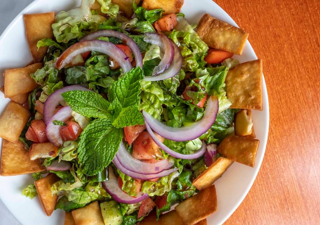 Fattoush · Lettuce, parsley, onions, tomato, cucumbers, sumac, and pomegranate dressing topped with fried pita bread.