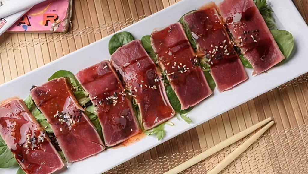 Tuna Tataki · Red tuna lightly seared, sliced, drizzled with sweet chili, ponzu and eel sauces and finished with a sprinkle of sesame seeds. A rare treat.