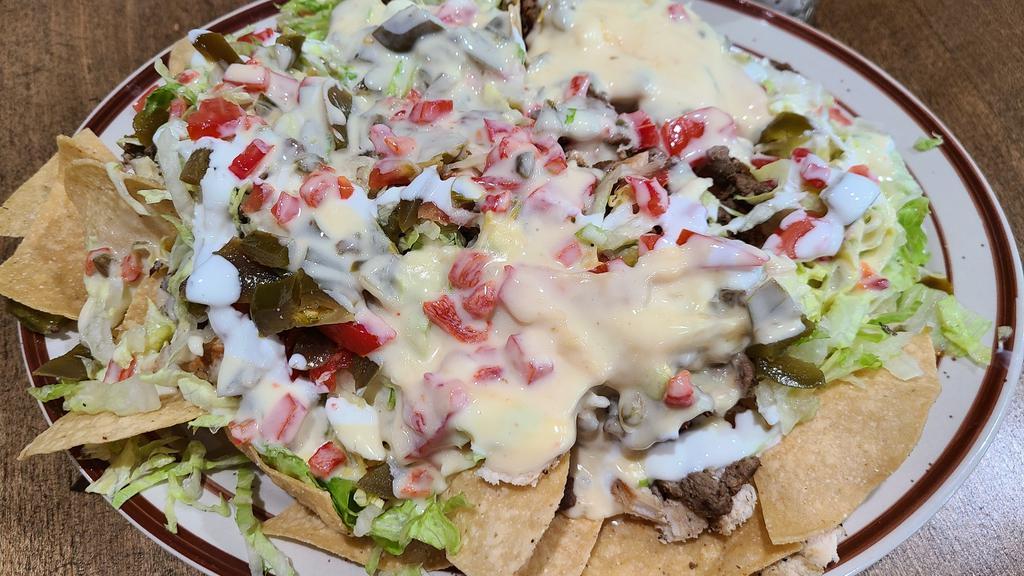 Nachos · Chips, white melted cheese,  lettuce,  tomato,  pickled jalapeños,  black beans ans queso fresco.