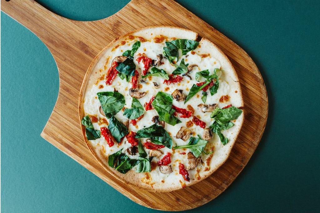 Sun & Shade Pizza · Sundried tomatoes, mushrooms, and mozzarella on an alfredo sauce base. Finished with fresh baby spinach and herb infused olive oil drizzle.