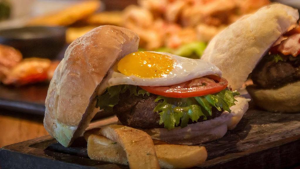 A Caballo Burger · Topped with sunny side up egg and aged cheddar cheese. Accompanied with potato chips, lettuce, and sliced tomato.