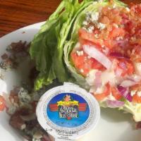 Wedge Salad · Crisp iceberg wedge with tomatoes, cucumbers, warm bacon crumbles, and crumbled bleu cheese ...