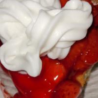 Strawberry Cheesecake · Creamy cheesecake with a graham cracker crust topped with strawberries in a sauce, served wi...