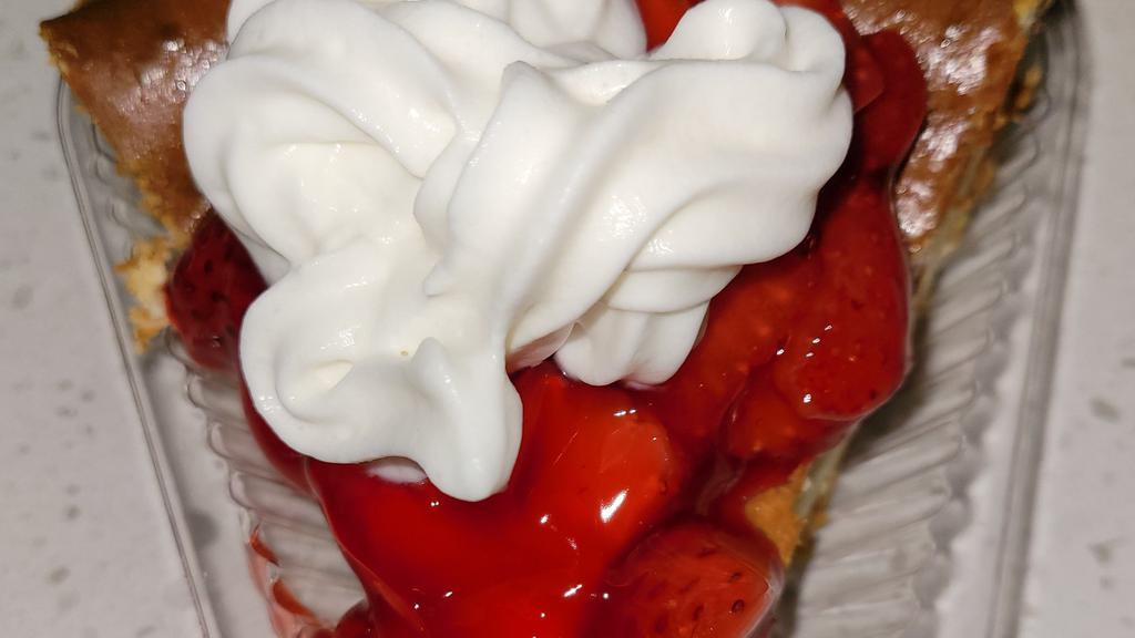 Strawberry Cheesecake · Creamy cheesecake with a graham cracker crust topped with strawberries in a sauce, served with whipped cream.
