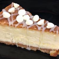 White Chocolate Cheesecake · White chocolate cheesecake slice with a graham cracker crust and a white ganache drizzle and...