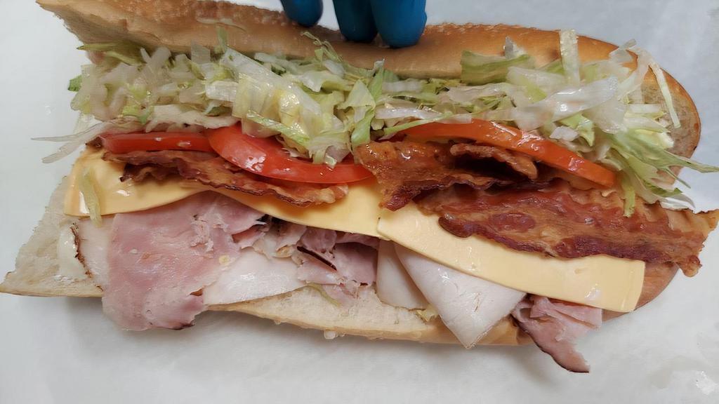 Turkey Club. · A trio of different meats in one sub. Ham, turkey, and fresh crispy bacon held in by slices of American cheese. This sub is topped with tomatoes, shredded lettuce, and an our oil and vinegar blend.