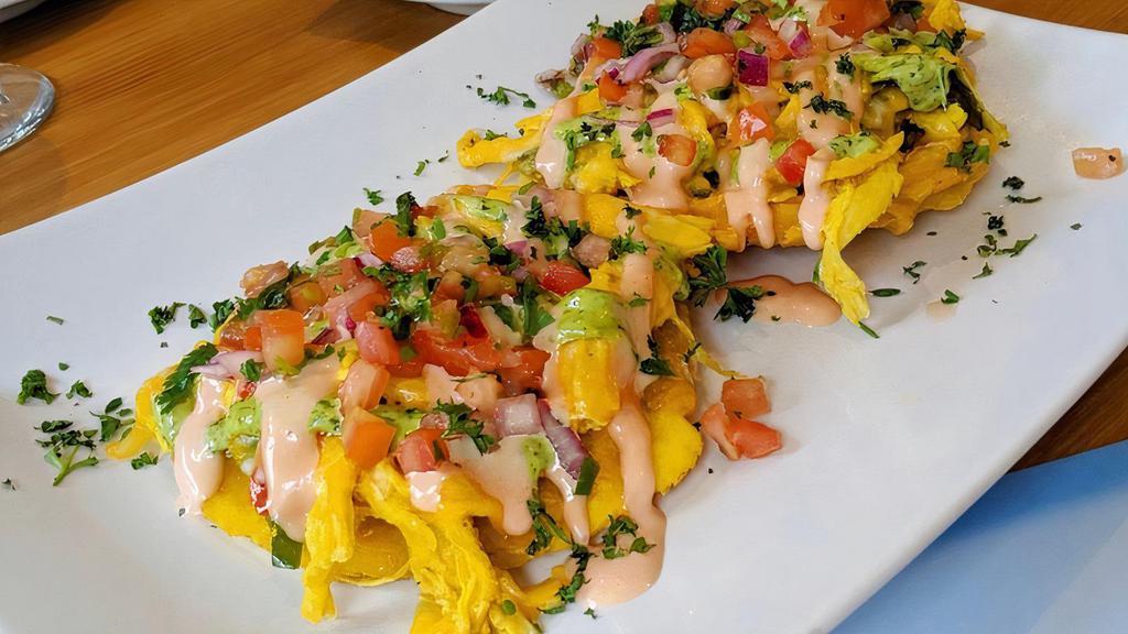 Tostones Con Pollo · Fried green plantains layered with shredded chicken, vegetables, melted cheese, pink and cilantro cremo, topped with pico de gallo.