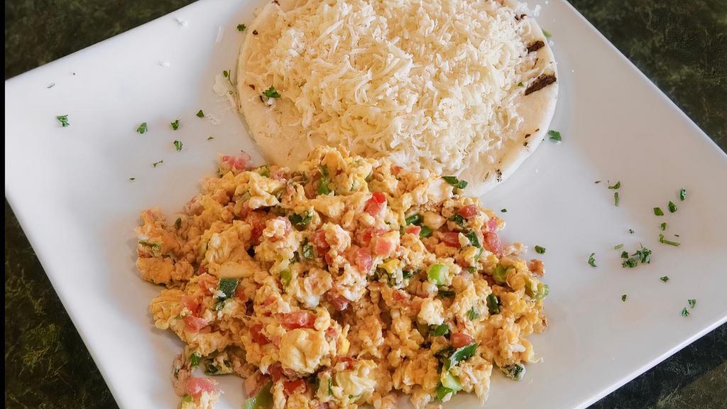 Huevos Perios · Three scrambled eggs with chopped tomatoes and green onions served with arepa and white cheese.
